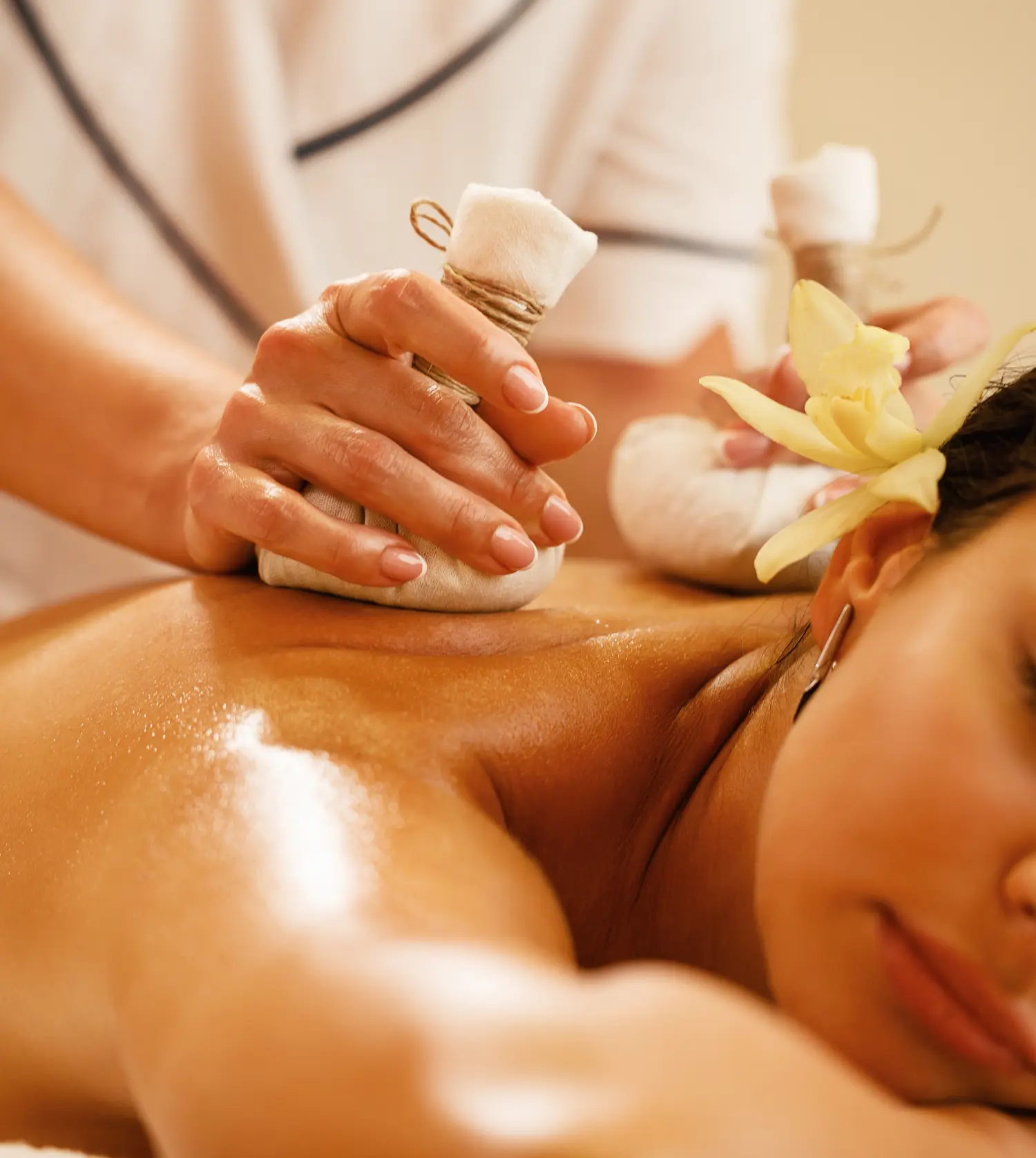 Therapist applying a hot compress to a client's back during her Signature Bliss Massage experience at Pause Spa