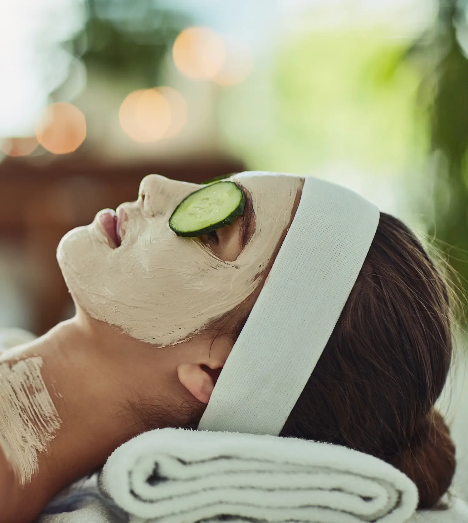 Woman wearing a white headband and a white face mask with cucumbers on her eyes during her Appetiser Facial experience at Pause Spa