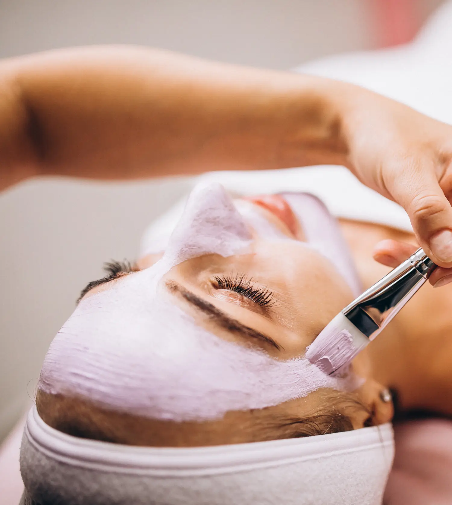 Therapist applying a face mask with a brush to a client's face during her Essential Phyto-Boost Facial treatment at Pause Spa