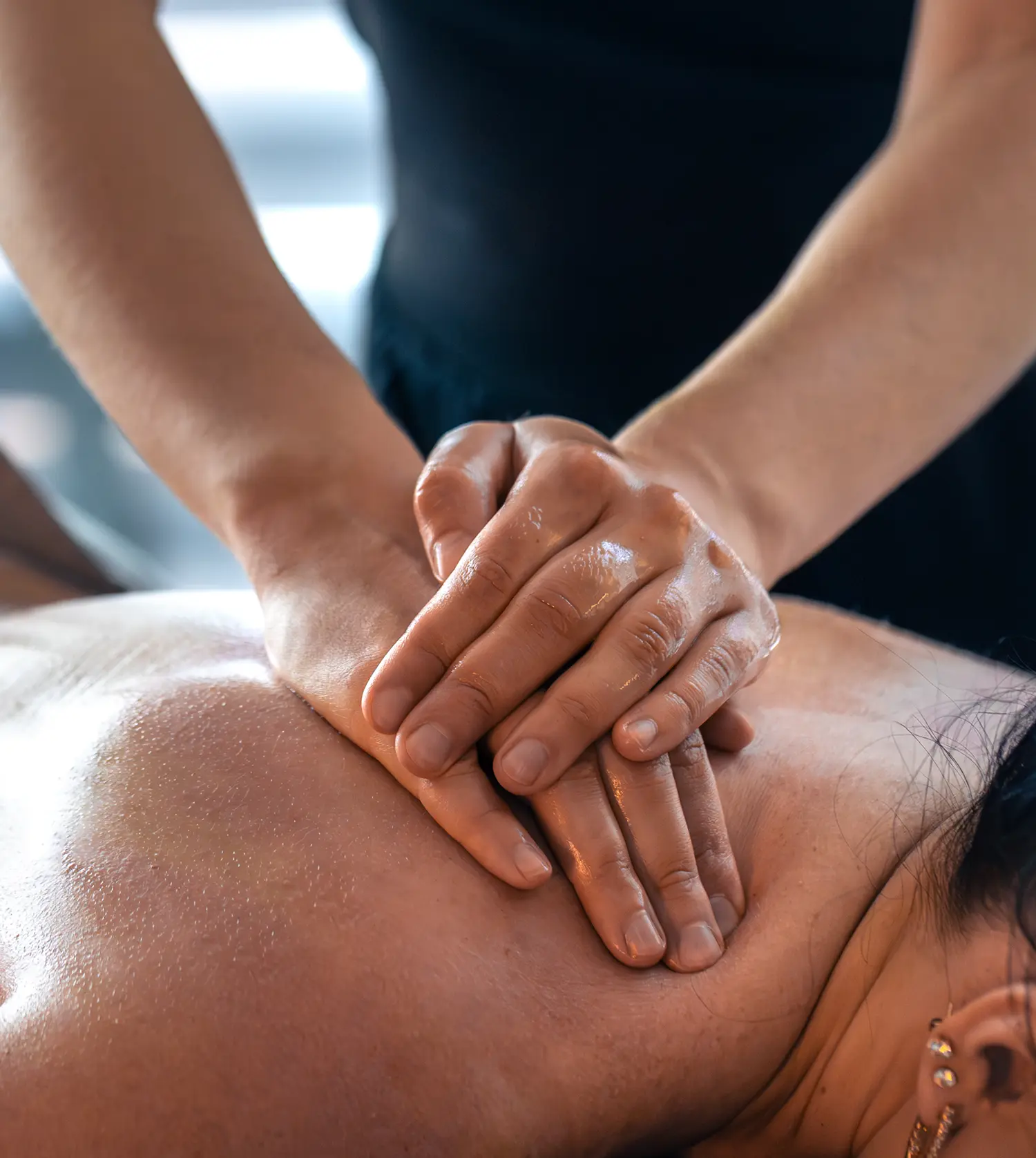 Therapist giving a woman a deep tissue shoulder massage as part of her Personalised Therapeutic Massage spa experience at Pause Spa