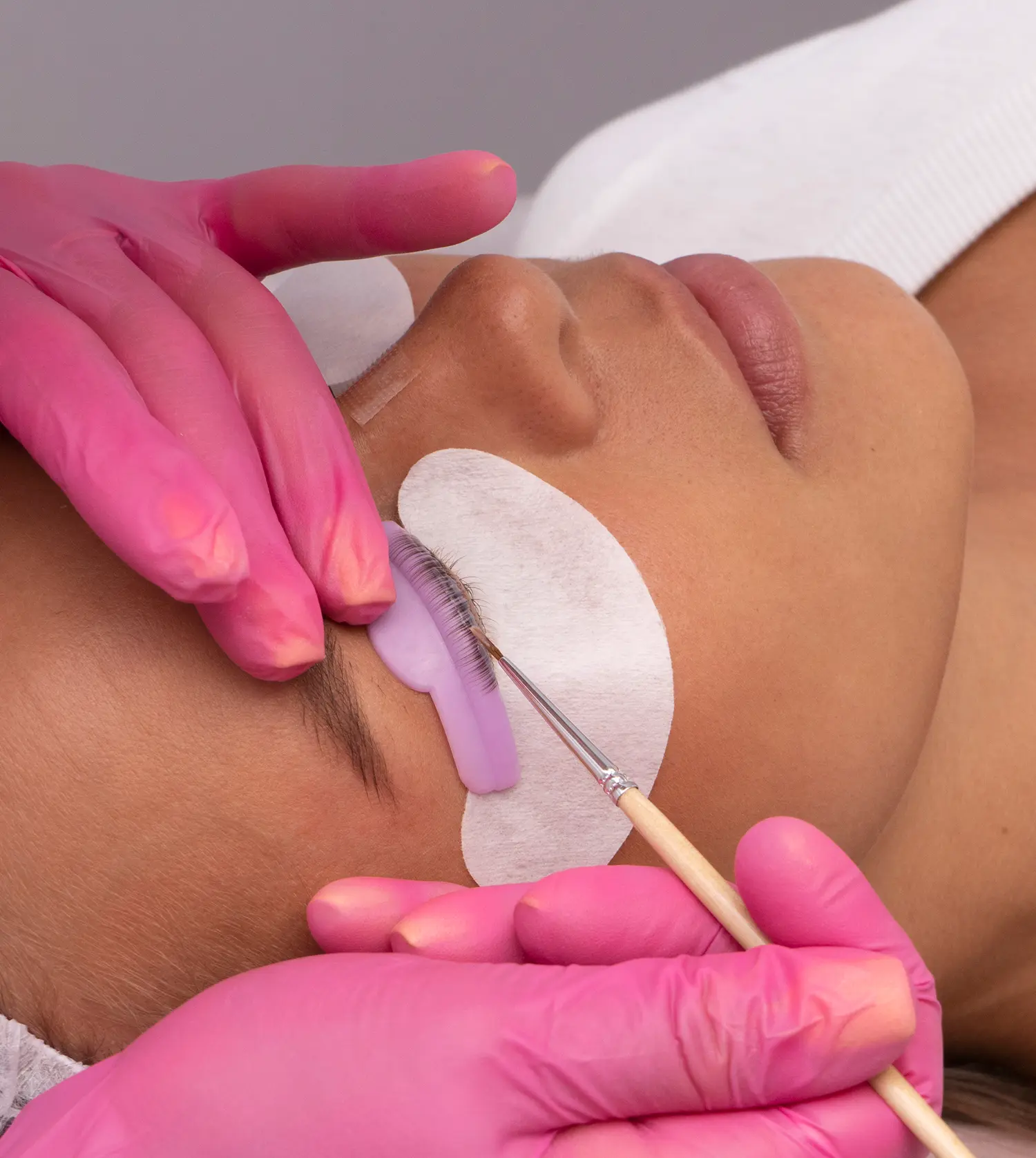 Therapist applying tint to a client's eyelashes and shaping her eyebrows during her Lash & Brow Tint & Shape experience at Pause Spa