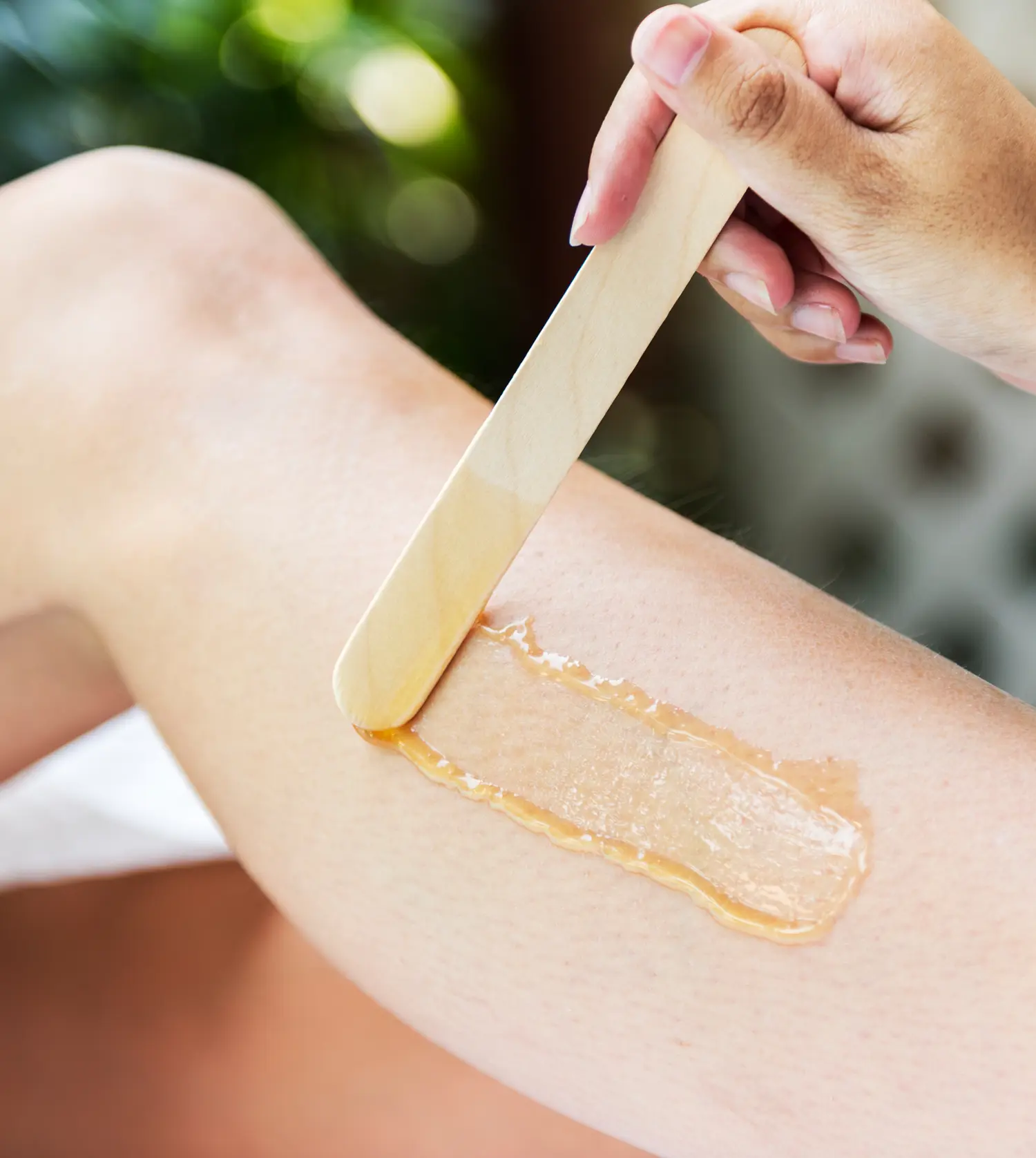 Therapist applying wax to a client's leg during her 3/4 Leg Wax experience at Pause Spa
