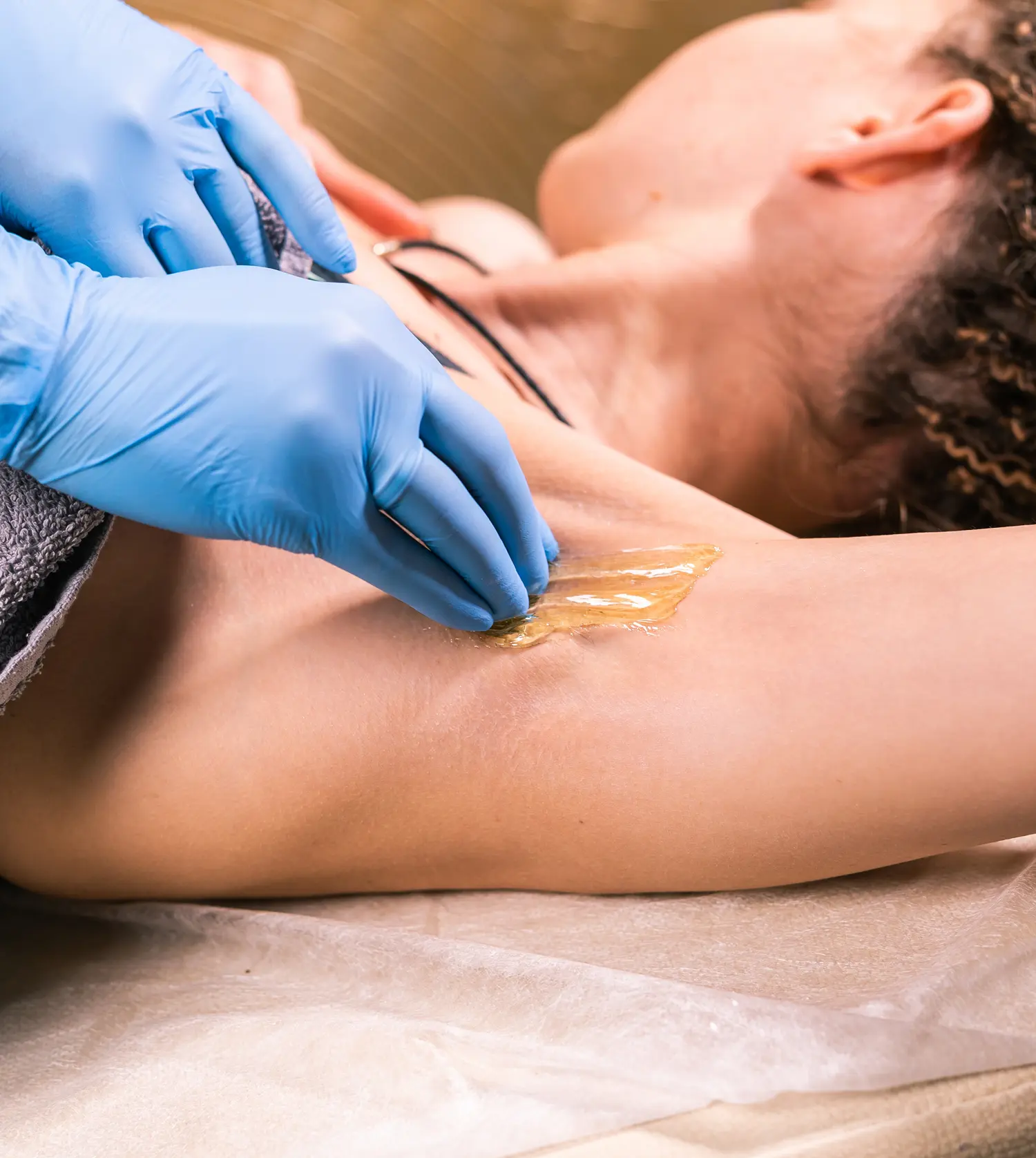 Therapist applying wax to a client's underarm during her Under Arm Wax experience at Pause Spa