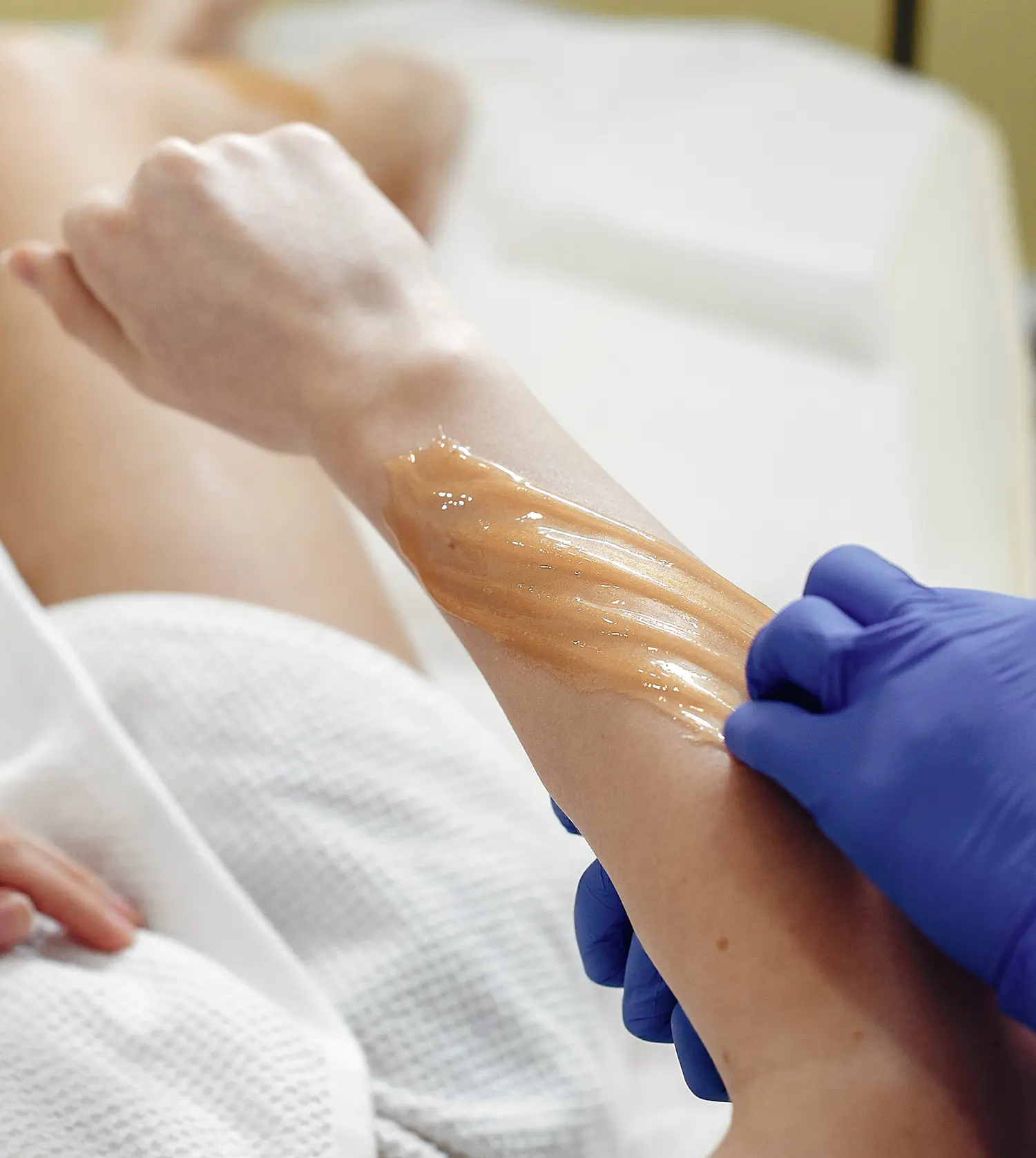 Therapist applying wax to a client's arm during her Full Arm Wax experience at Pause Spa